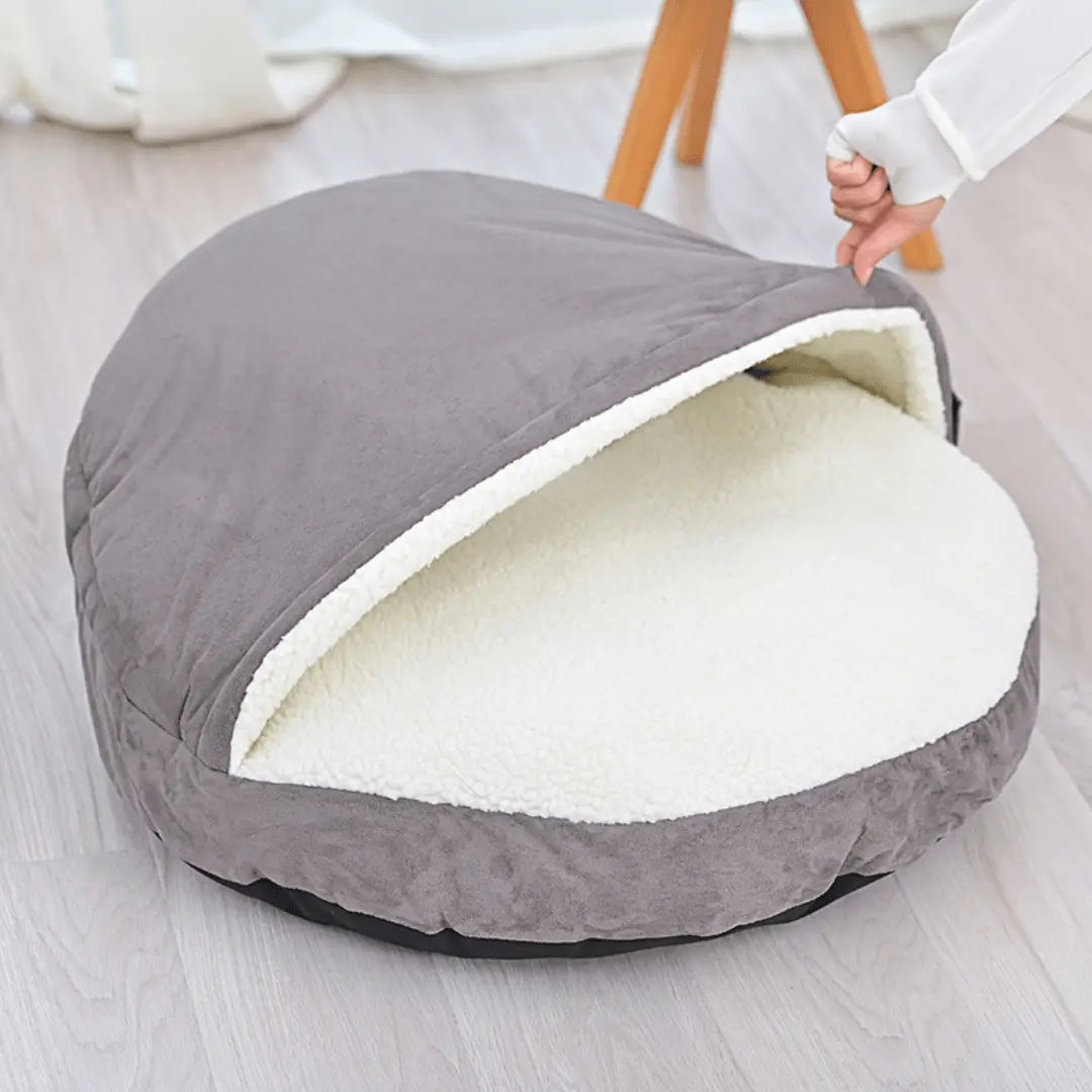 Calming Ultimate Anti-Anxiety Dog Bed – Cozy Hooded BedGray pet bed with white interior on a light wooden floorJoypup